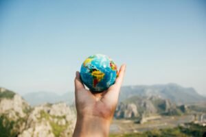 Contacto Riqueza Mediterranea Murcia - Hand holding a globe against a mountain background symbolizing travel and exploration.